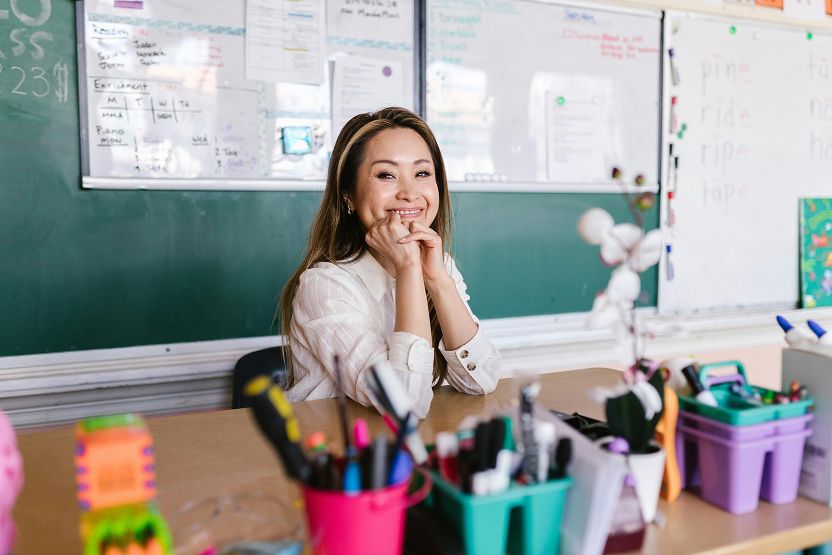 A teacher smiling behind her desk
